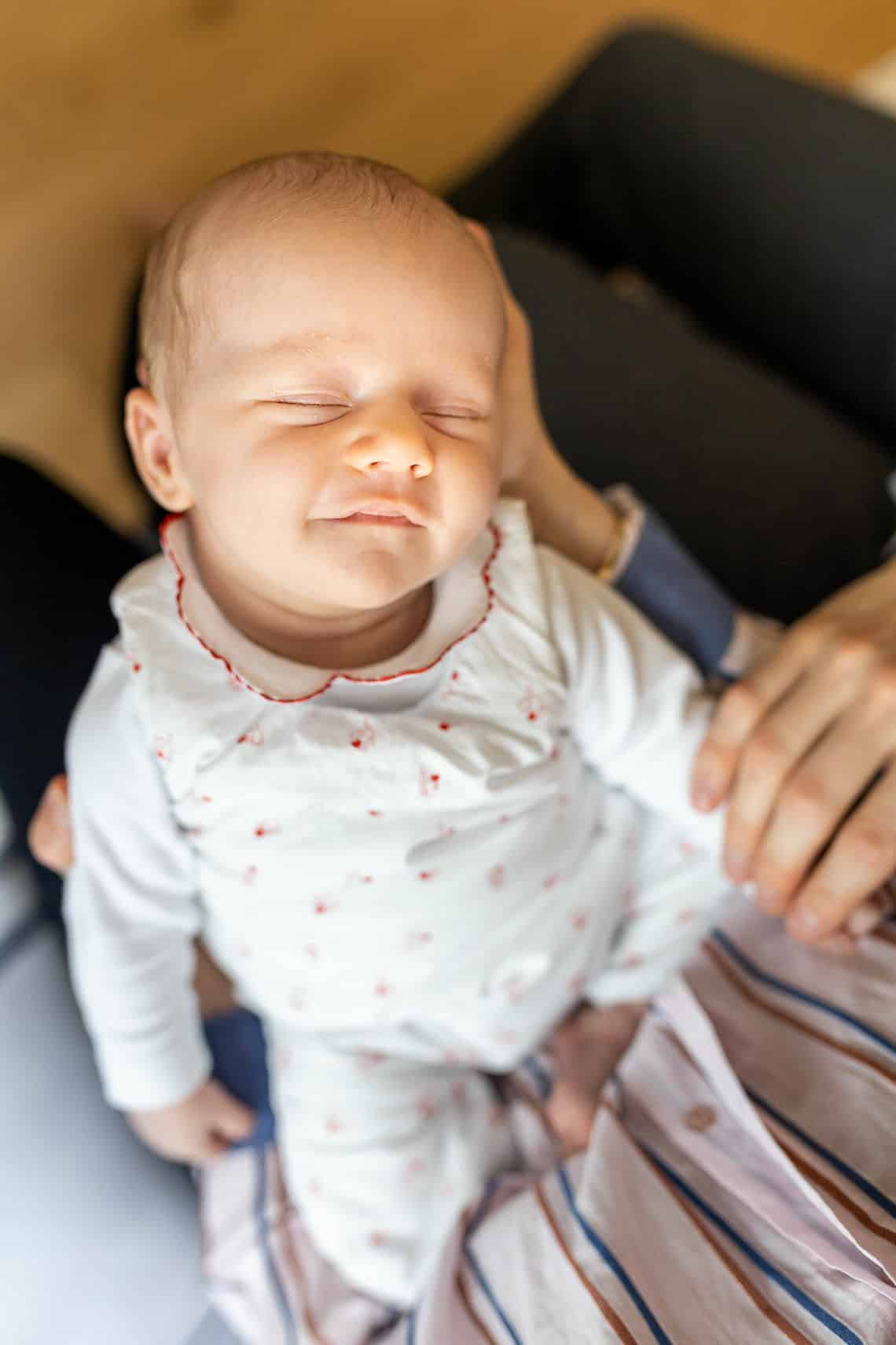 bébé qui sourit dans les bras de ses parents